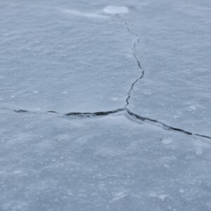 A close-up shows cracks in a sheet of frozen concrete